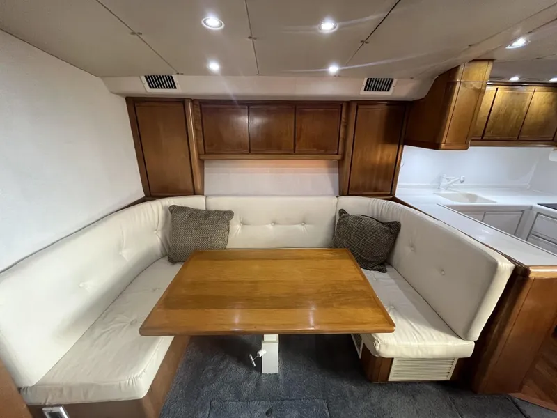 Slide: The Image of 1993 Bertram 46 Moppie yacht interior with cushioned seating and wooden table. - 4