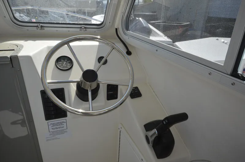 Slide: The Image of 2023 May-Craft 23 Pilothouse helm with steering wheel and throttle controls. - 10