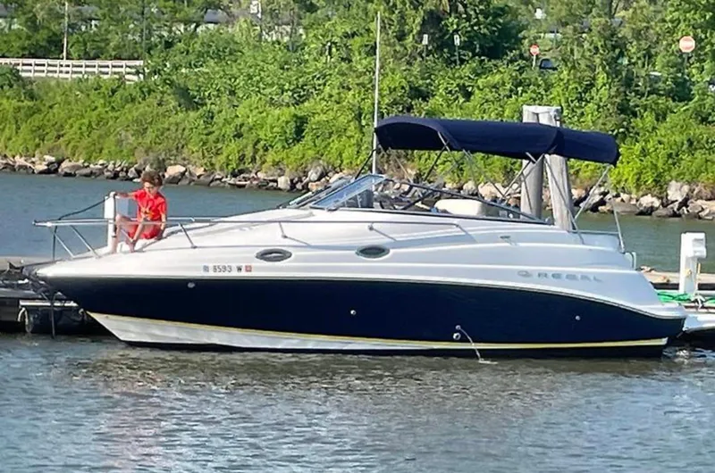 The Image of 2005 Regal Commodore 2665 boat docked on a calm river with lush greenery. - 0