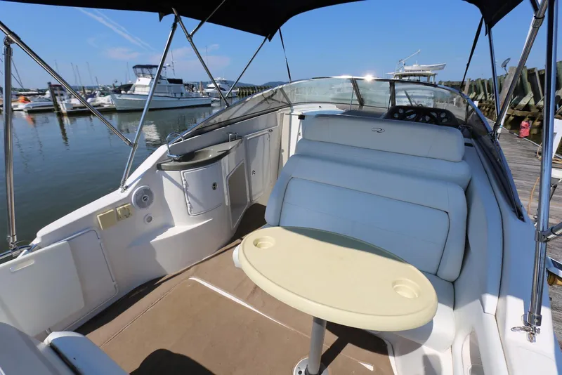 Slide: The Image of 2005 Regal Commodore 2665 boat interior with seating and table at a marina. - 10