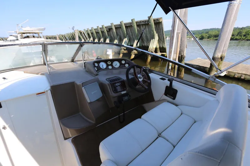 Slide: The Image of 2005 Regal Commodore 2665 boat interior with steering wheel and dashboard, docked by wooden pier. - 11
