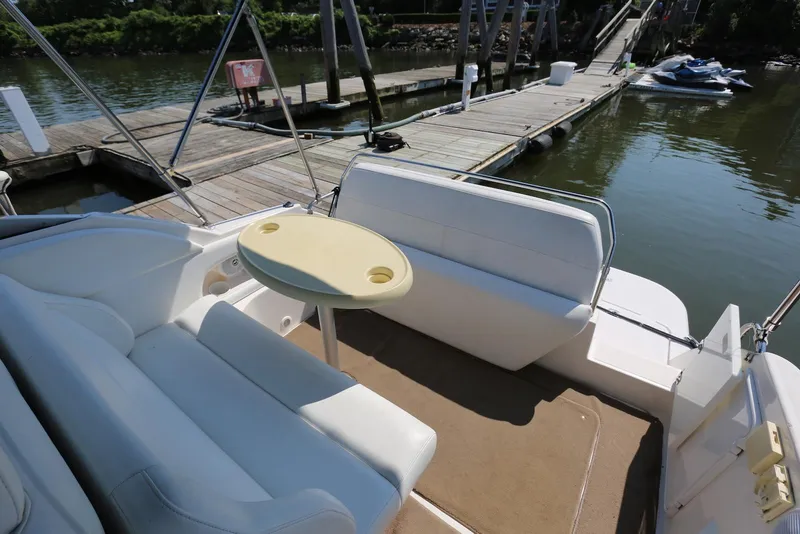 Slide: The Image of 2005 Regal Commodore 2665 boat interior with seating and table, docked by a wooden pier. - 12