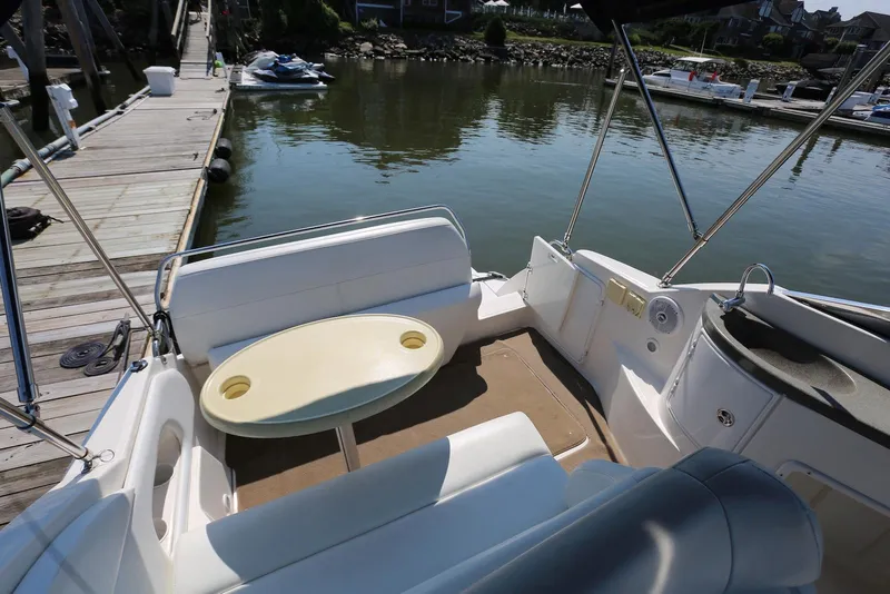 Slide: The Image of 2005 Regal Commodore 2665 boat interior with seating and table, docked by the water. - 13