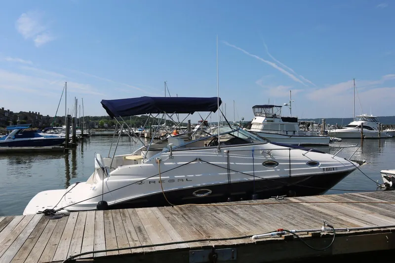 Slide: The Image of 2005 Regal Commodore 2665 boat docked at a marina under a clear blue sky. - 2