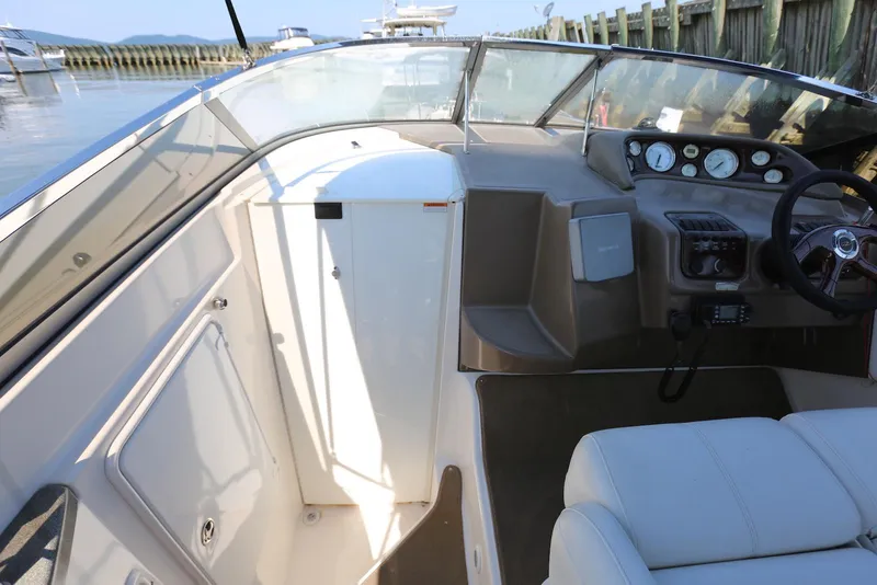 Slide: The Image of 2005 Regal Commodore 2665 boat interior with dashboard and seating, docked by wooden pier. - 30