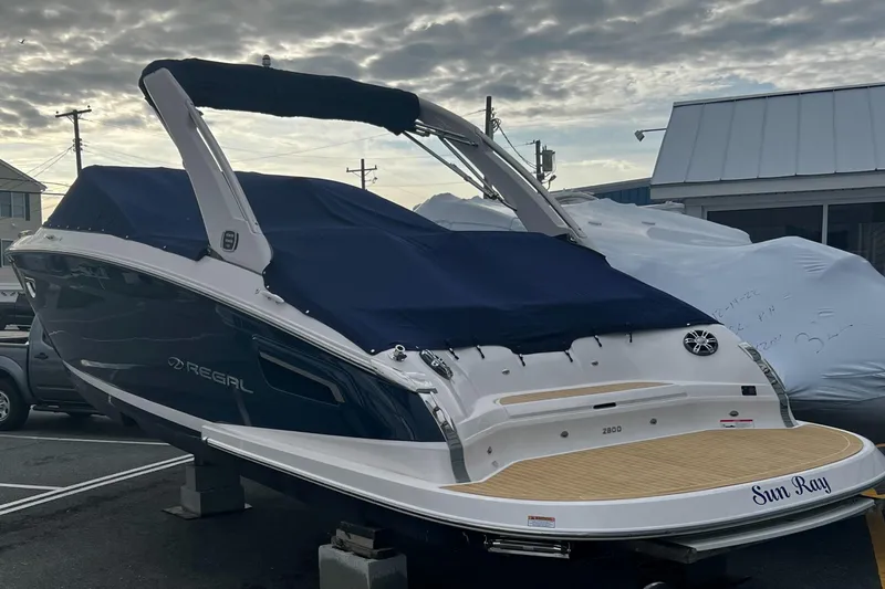 Slide: The Image of 2019 Regal 2800 Bowrider boat with blue cover, docked outdoors. - 2