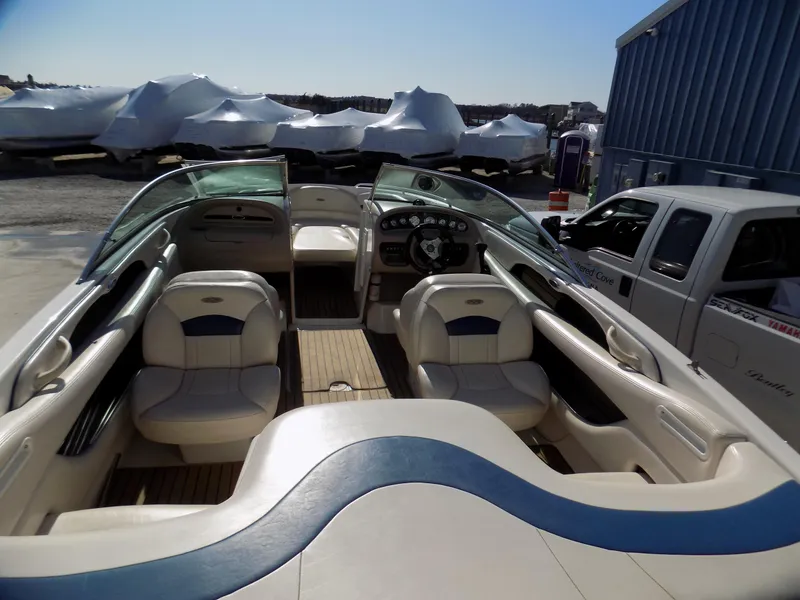 Slide: The Image of 2001 Chaparral 216 SSi boat interior with seating and dashboard, parked near covered boats. - 3