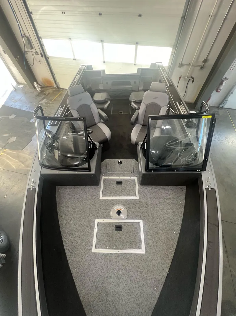Slide: The Image of 2023 Starcraft Fishmaster 196 boat interior with seating and open windshield in a garage. - 3