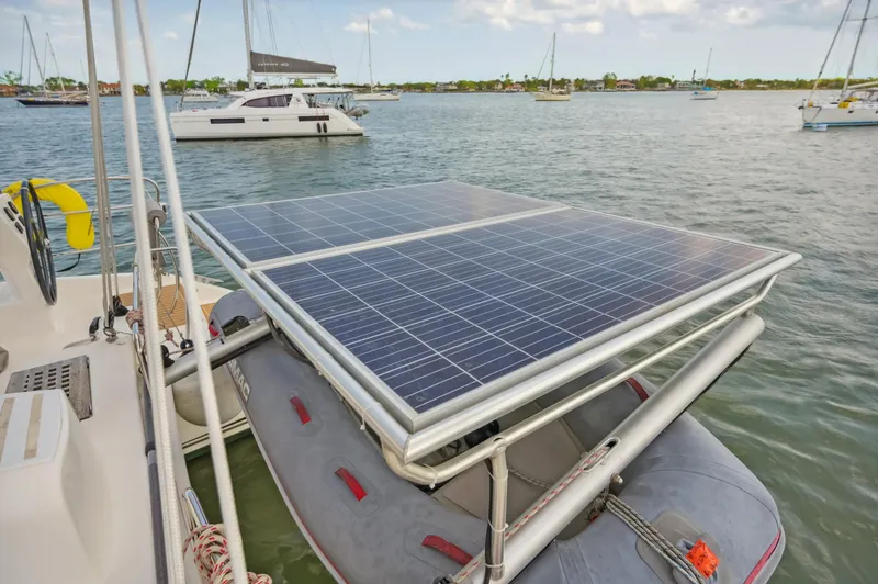 Slide: The Image of Catana 42 catamaran with solar panels and dinghy, anchored in a scenic bay. - 14