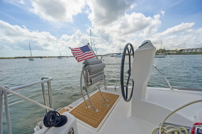 Slide: The Image of Catana 42 sailboat deck with American flag, steering wheel, and scenic water view. - 15