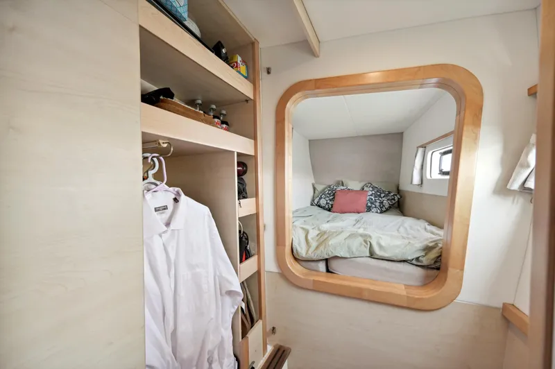Slide: The Image of Catana 42 yacht interior, cozy bedroom with window, wooden accents, and closet space. - 32