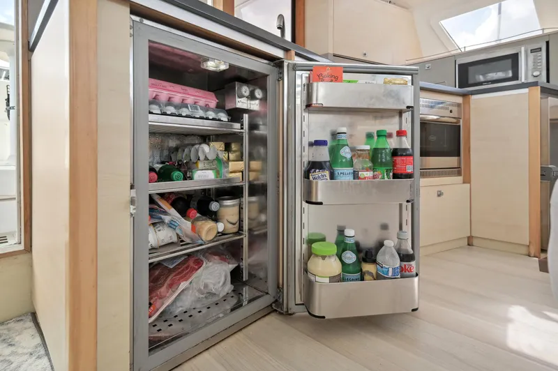 Slide: The Image of Open fridge in Catana 42 yacht kitchen, stocked with beverages and groceries. - 42
