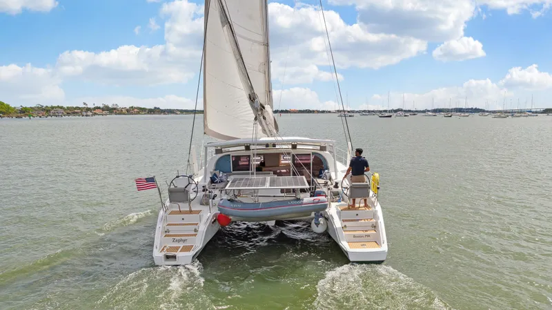 Slide: The Image of Catana 42 catamaran sailing on open water, 2016 model, rear view with American flag. - 8