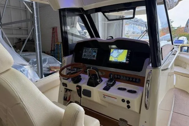 Slide: The Image of 2019 Chris-Craft Catalina 30 helm with navigation screens and controls in a marina setting. - 13