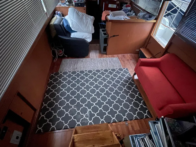 Slide: The Image of Interior of a 1968 Chris-Craft Commander with red sofa, patterned rug, and wooden flooring. - 13