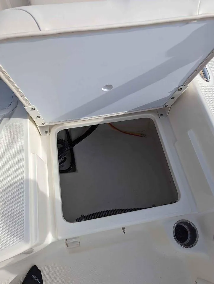 Slide: The Image of 2023 Sundance DX22 boat storage compartment with open hatch. - 12