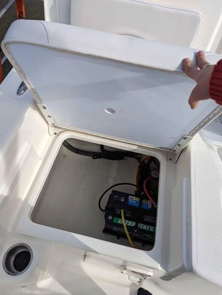 Slide: The Image of 2023 Sundance DX22 boat battery compartment with lid open. - 15