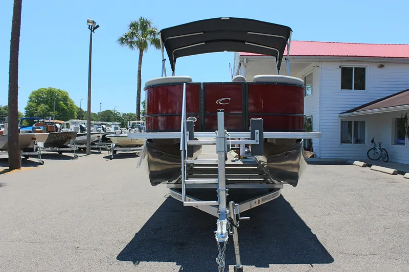 Slide: The Image of 2023 Crest Classic 200 LX L pontoon boat on trailer in marina. - 2