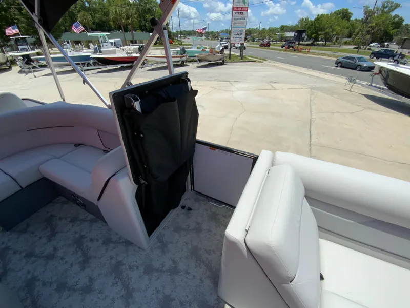 Slide: The Image of 2023 Crest Classic LX 220 SF boat interior with white seating and open storage compartment. - 13