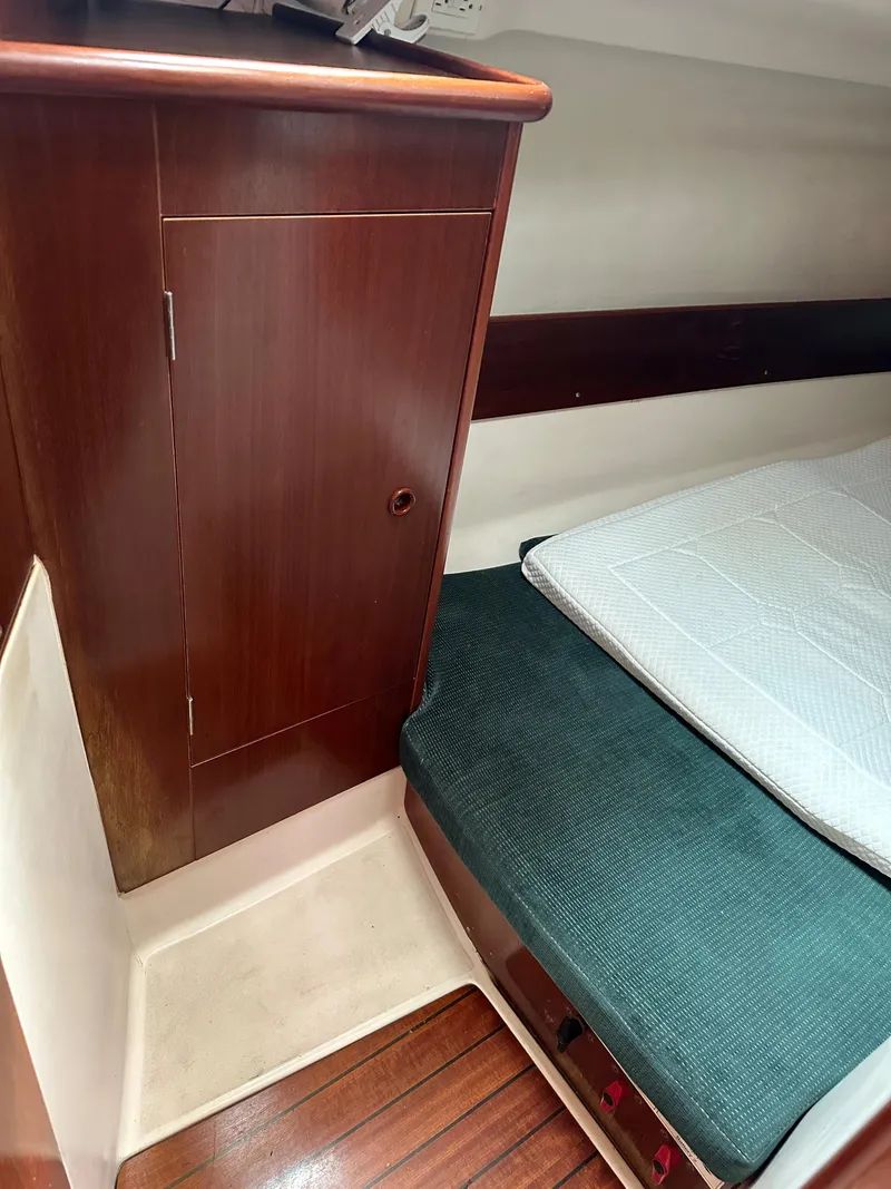 Slide: The Image of Interior cabin of 2000 Beneteau Oceanis 321 sailboat with wooden cabinetry and cozy bedding. - 19