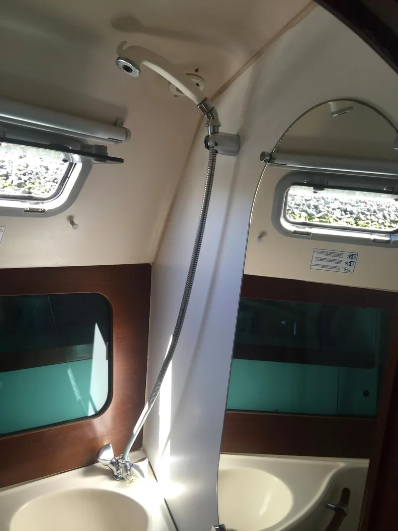 Slide: The Image of Beneteau Oceanis 321 (2000) yacht bathroom with shower, sink, and windows. - 33