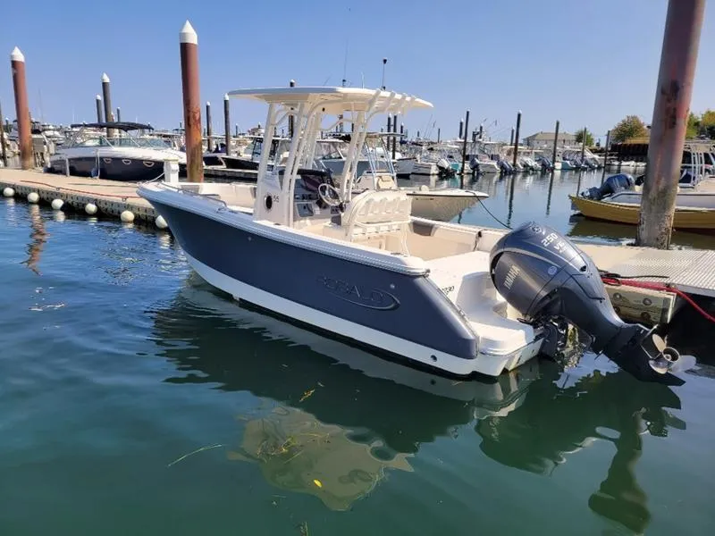 Slide: The Image of 2023 Robalo R230 boat docked in a marina, featuring sleek design and powerful outboard motor. - 12