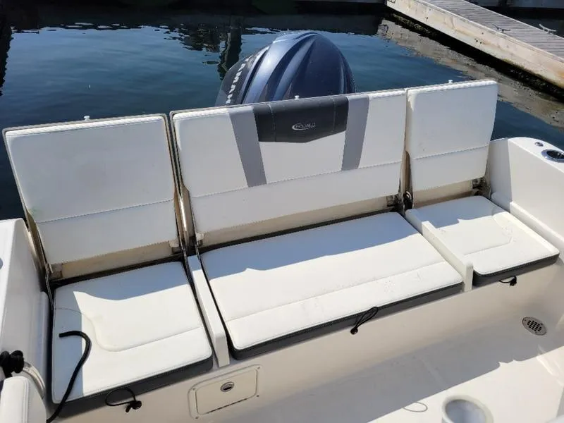 Slide: The Image of 2023 Robalo R230 boat seating area with cushioned seats and outboard motor. - 13