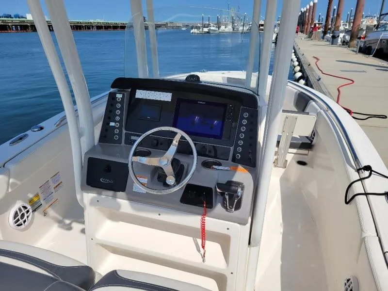 Slide: The Image of 2023 Robalo R230 boat dashboard with steering wheel and navigation system at a marina. - 5