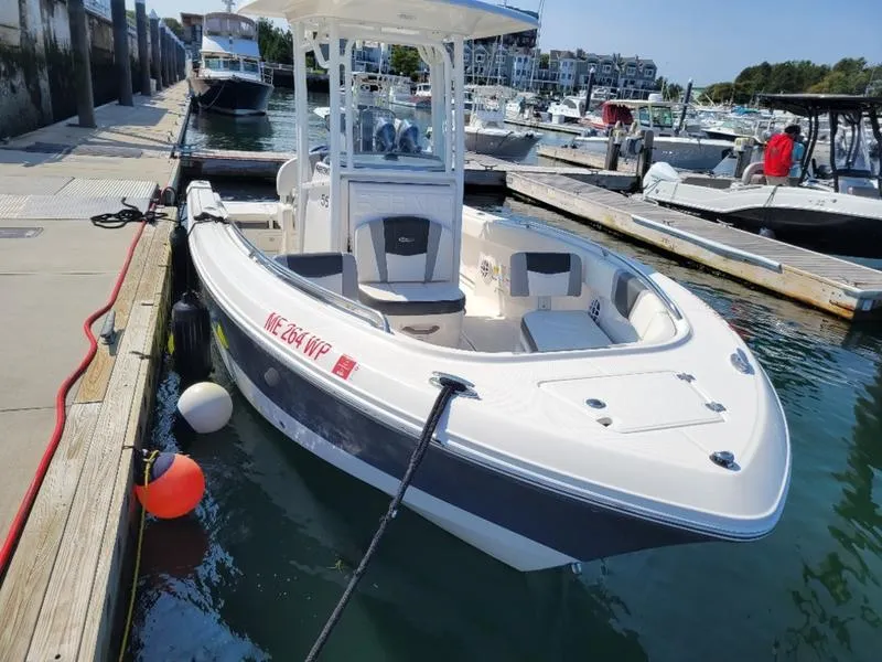 Slide: The Image of 2023 Robalo R230 boat docked at marina, featuring sleek design and spacious deck. - 8