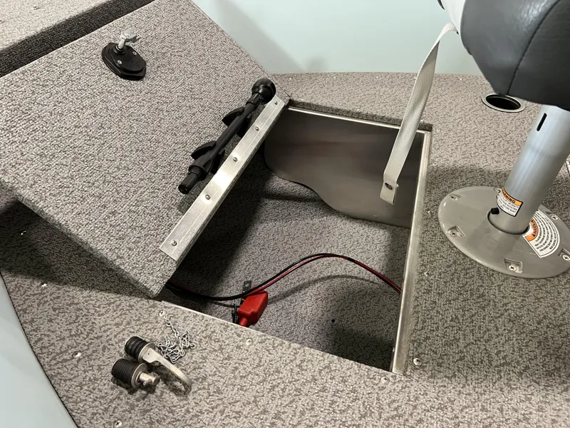 Slide: The Image of 2023 Starcraft Patriot 16 TL boat interior with open storage compartment and seat pedestal. - 5