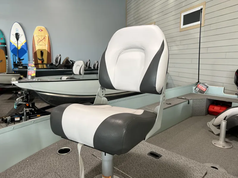 Slide: The Image of 2023 Starcraft Patriot 16 TL boat interior with cushioned seating and paddleboards in the background. - 6