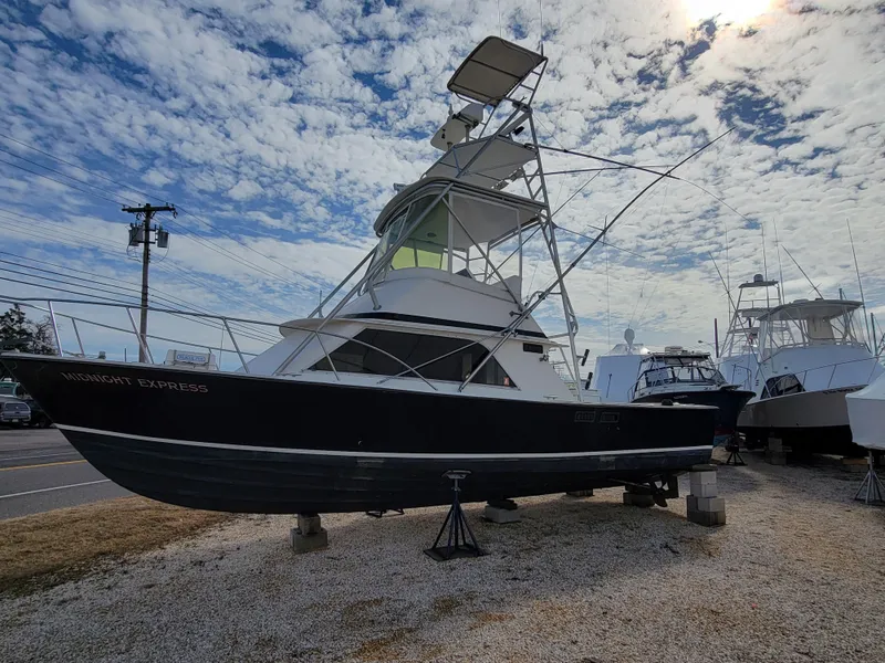 The Image of 1980 Blackfin 32 Flybridge boat on dry dock under a partly cloudy sky. - 0