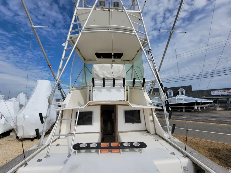 Slide: The Image of 1980 Blackfin 32 Flybridge boat with fishing rod holders and flybridge, docked under a blue sky. - 16