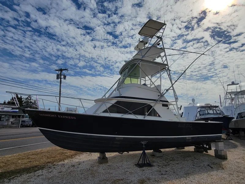 Slide: The Image of 1980 Blackfin 32 Flybridge boat on dry dock under a partly cloudy sky. - 3