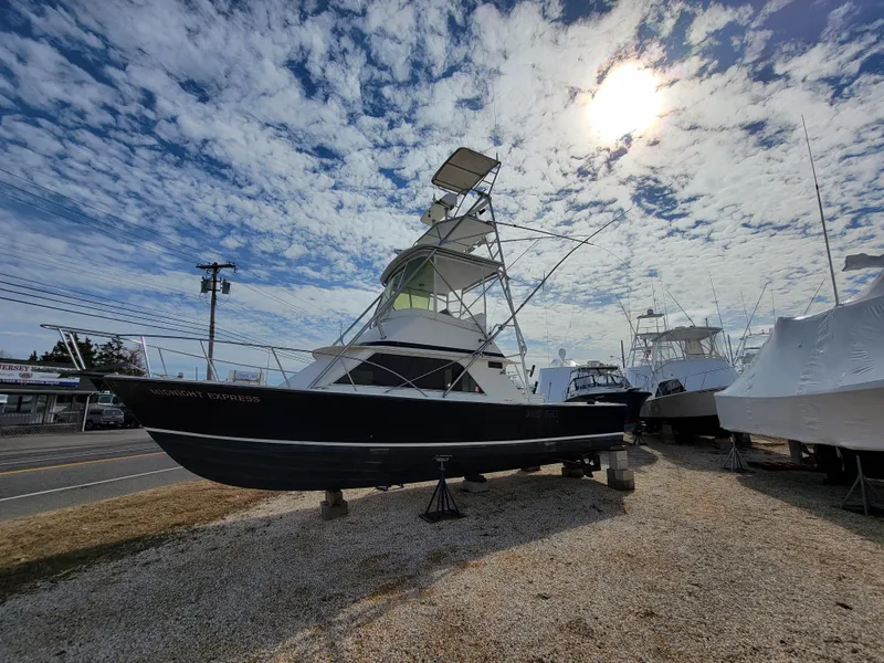 Slide: The Image of 1980 Blackfin 32 Flybridge boat on dry dock under a partly cloudy sky. - 8