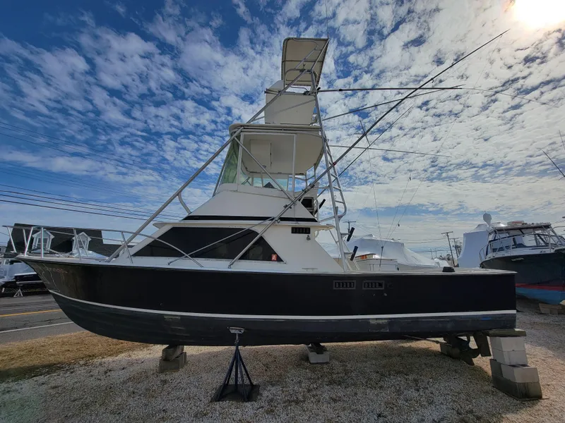 Slide: The Image of 1980 Blackfin 32 Flybridge boat on dry dock under a partly cloudy sky. - 9