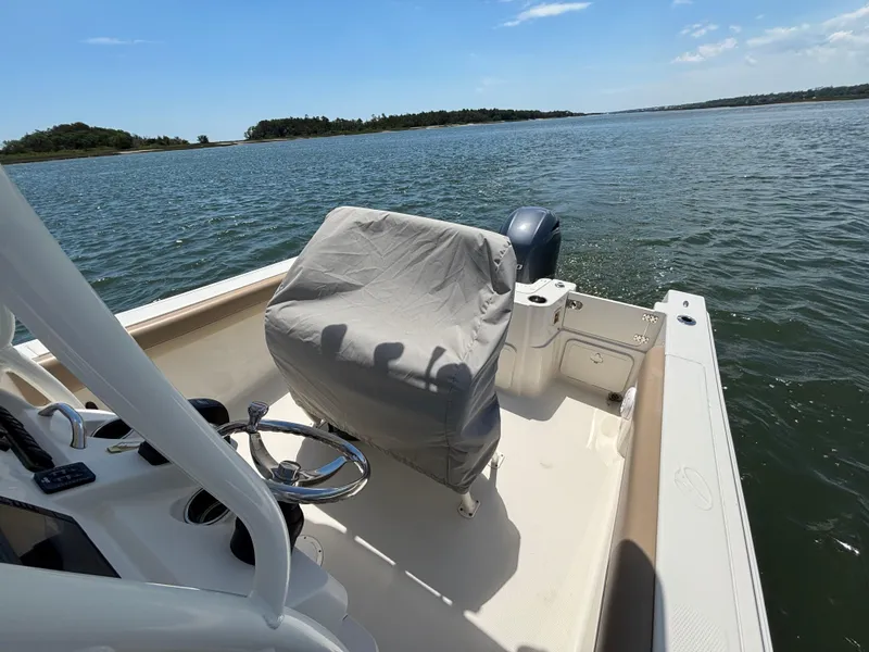 Slide: The Image of 2020 Sailfish 220 CC boat on calm water, featuring covered seating and steering wheel. - 12