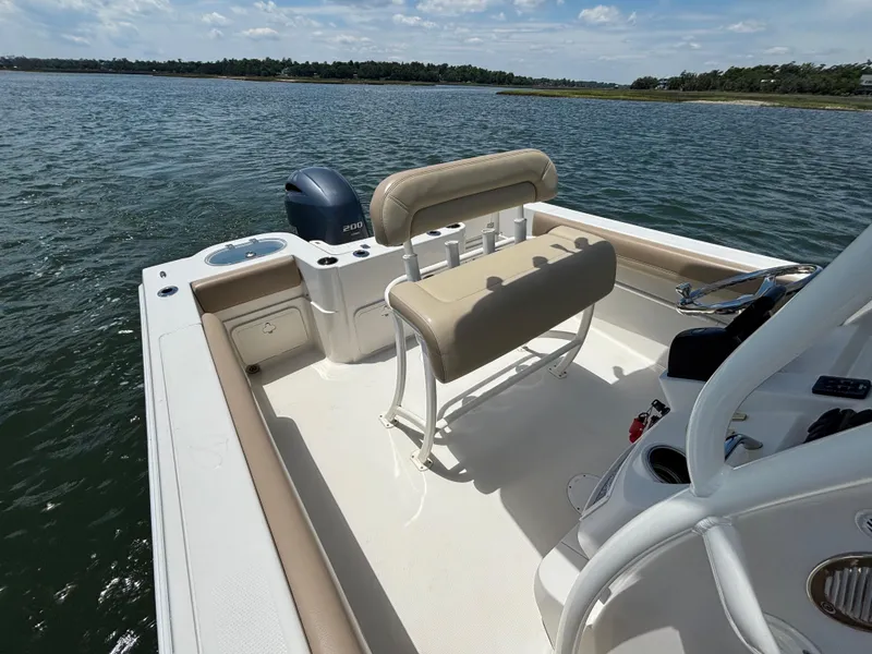 Slide: The Image of 2020 Sailfish 220 CC boat interior with seating and outboard motor on a sunny day. - 14