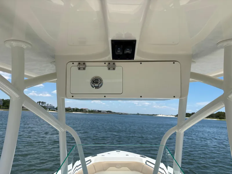 Slide: The Image of 2020 Sailfish 220 CC boat console with storage compartment, overlooking serene water and sky. - 27
