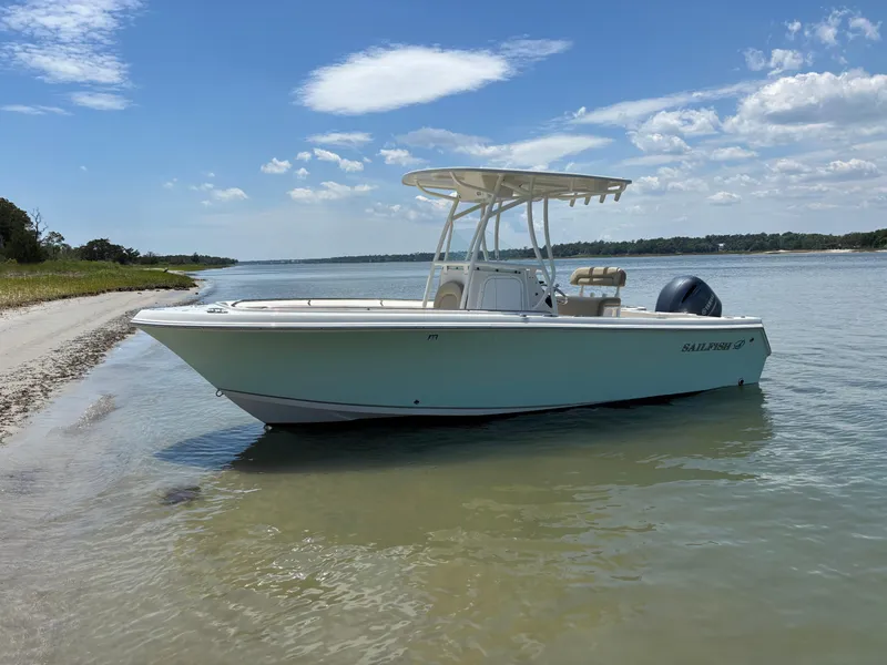 Slide: The Image of 2020 Sailfish 220 CC boat anchored near a sandy shore under a clear blue sky. - 30