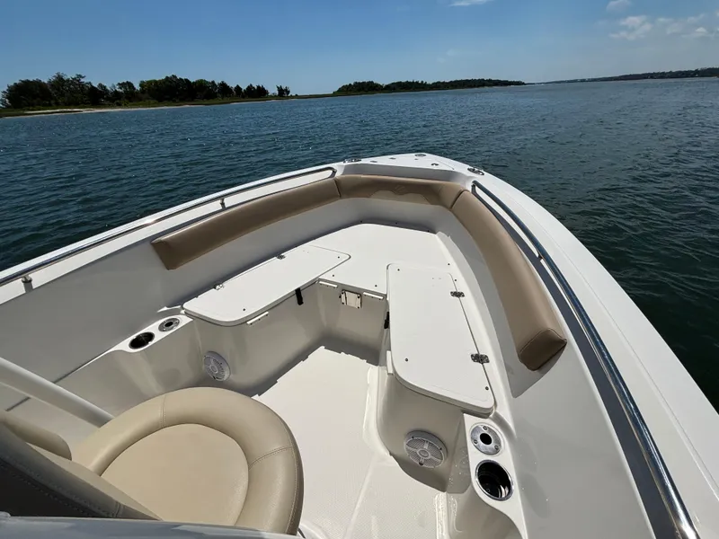 Slide: The Image of 2020 Sailfish 220 CC boat interior with seating, cup holders, and storage, on calm water. - 4