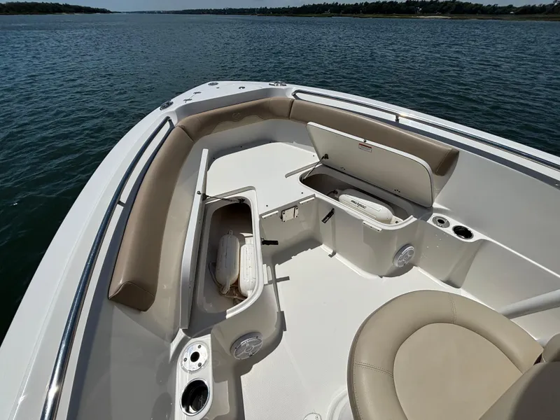 Slide: The Image of 2020 Sailfish 220 CC boat interior with seating and storage compartments on calm water. - 6
