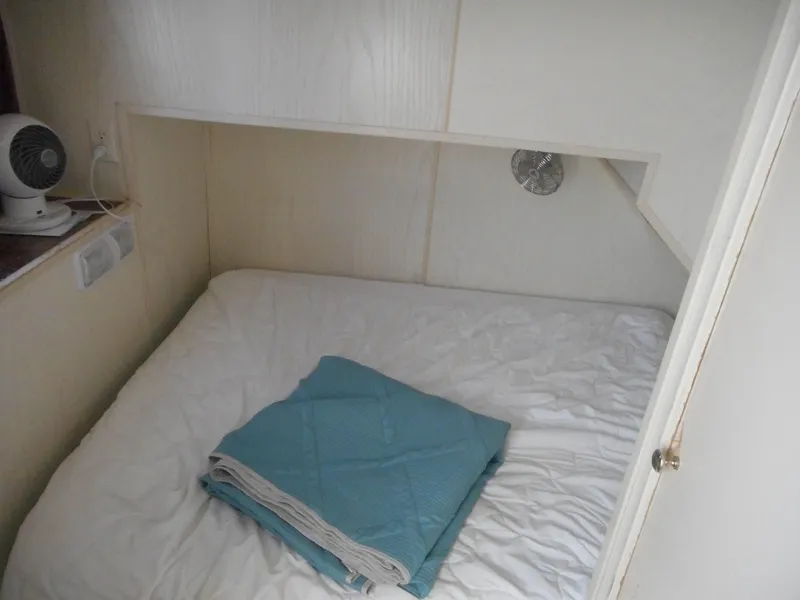 Slide: The Image of Small cozy cabin bed with folded blue blanket on a Stardust Cruisers houseboat. - 18