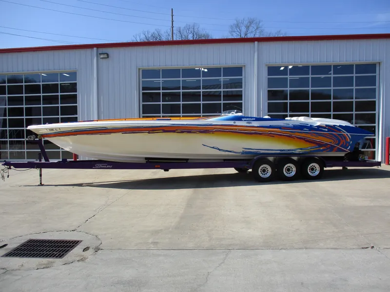 The Image of 2002 Hustler 388 SLINGSHOT speedboat with vibrant graphics on a trailer. - 1