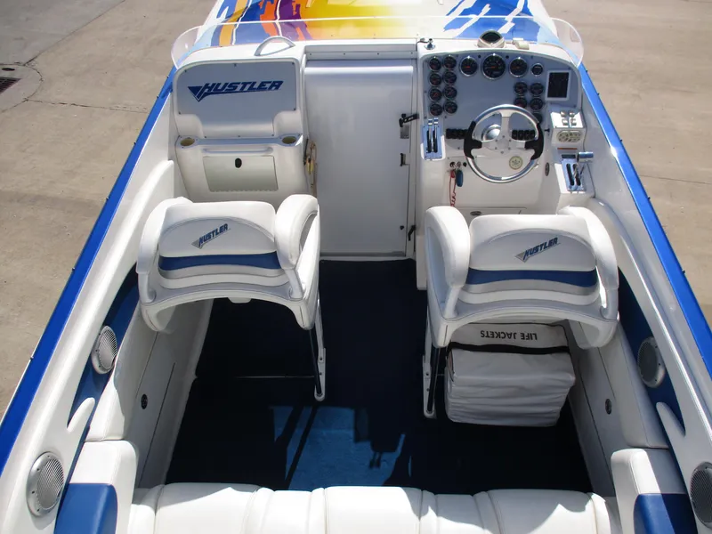 Slide: The Image of 2002 Hustler 388 SLINGSHOT boat interior with white and blue seating, steering console, and dashboard. - 11