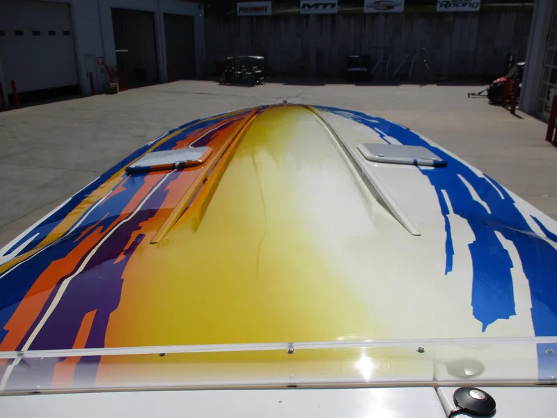 Slide: The Image of 2002 Hustler 388 SLINGSHOT boat with vibrant yellow, blue, and orange paint. - 19