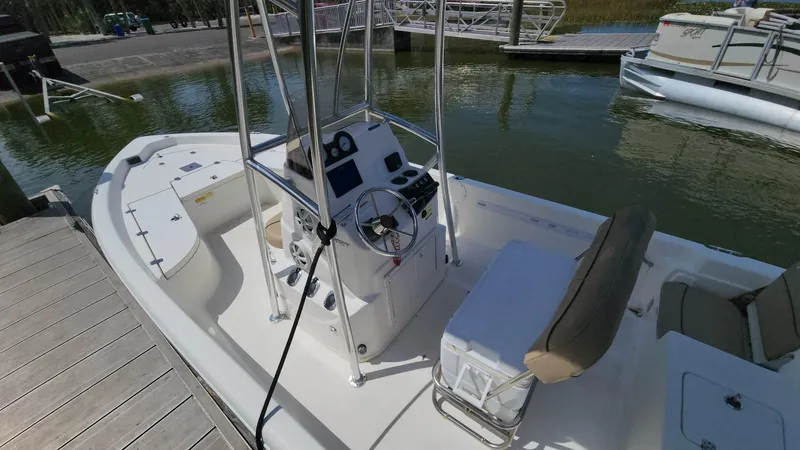 Slide: The Image of 2020 NauticStar 2140 Sport boat docked, featuring a center console and seating. - 16