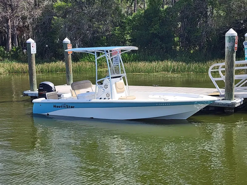 Slide: The Image of 2020 NauticStar 2140 Sport boat docked in a serene lake setting. - 2