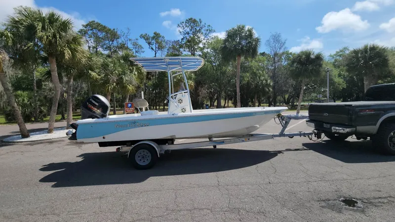 Slide: The Image of 2020 NauticStar 2140 Sport boat on trailer, parked near palm trees. - 27