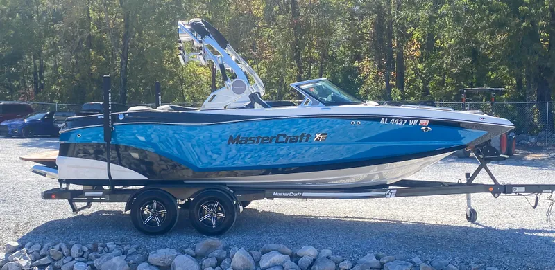 Slide: The Image of 2021 MasterCraft XT22 boat on trailer, blue and white, parked outdoors. - 5
